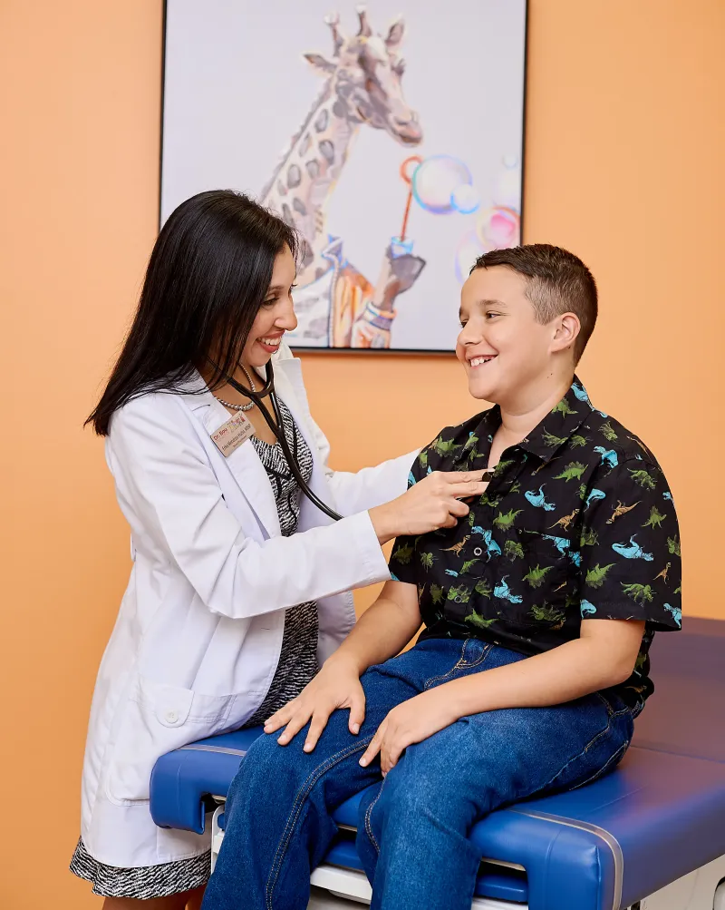 Our nurse practitioner listening to a smiling child's heart with a stethoscope